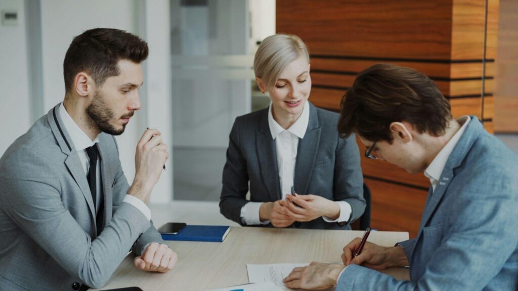 Man signing contract with a slip and fall attorney explaining legal details at a modern office table.