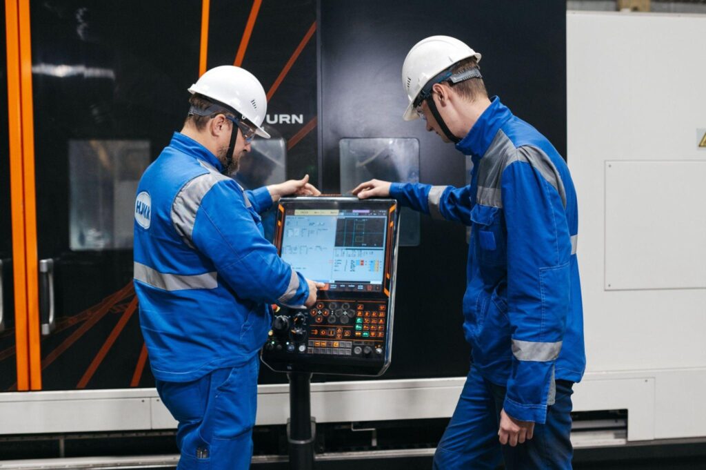 Technicians reviewing a control panel display for industrial equipment.